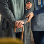 Nurse assisting senior with walking cane