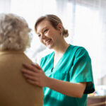 Friendly home caregiver supporting an elderly lady