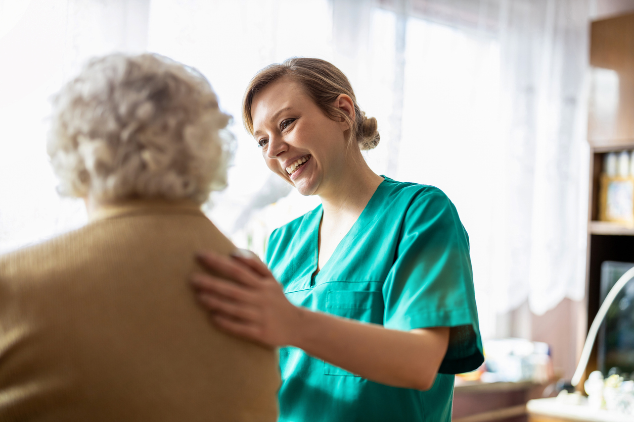 Friendly home caregiver supporting an elderly lady