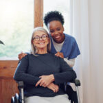 Senior care, nurse and old woman with wheelchair, portrait and smile in health at nursing home. Support, kindness and happy face of caregiver with elderly person with disability for homecare service.