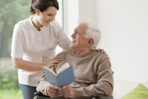 Photo of elderly man reading book and his personal home assistence