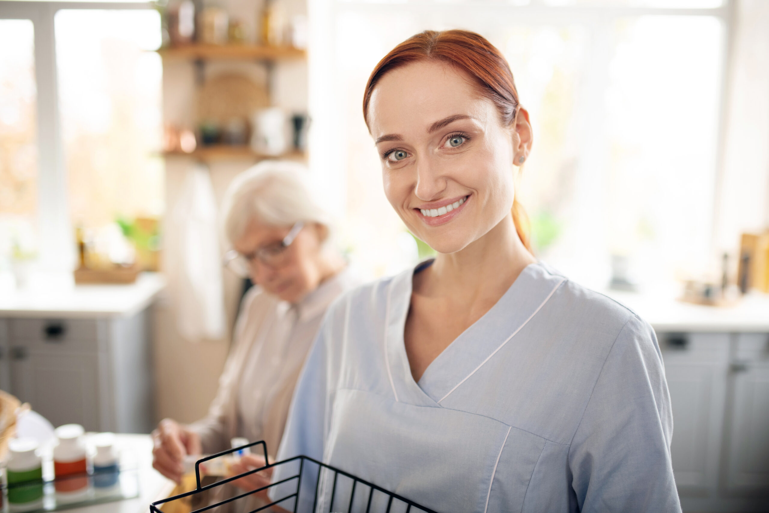 Smiling young caregiver assisting an elderly woman in a home setting, representing compassionate home health care services in Allentown, PA.