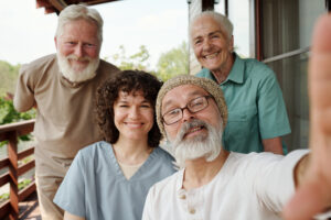 Happy young caregiver with a group of senior individuals enjoying time together on a porch. Personalized senior care in Harrisburg, PA.