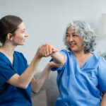 A compassionate home health caregiver assisting an elderly woman with physical therapy in Allentown, PA. Professional in-home care support by AmeriBest Home Care.